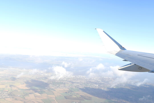 Beautiful horizon blue sky with white wing of airplane fiying above white clouds. View from airplane window © Eddy