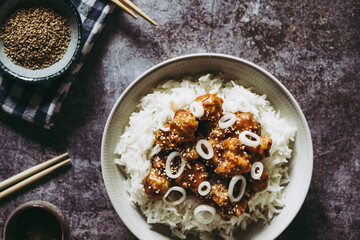 Choux-fleur caramélisé aux graines de sésame et petits oignons accompagné de riz blanc dans une assiette - Plat gourmand asiatique