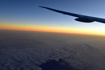 Silhouette of Airplan wing in twilight sky, with beautiful light from dramatic sunset, Romantic view from airplane window.