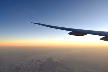 Silhouette of Airplan wing in twilight sky, with beautiful light from dramatic sunset, Romantic view from airplane window.