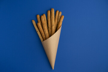 Grissini sticks wrapped in paper on a bright blue background