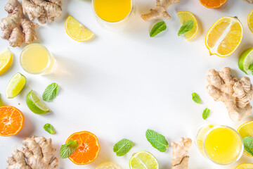 Immunity booster drink ingredients. Homemade ginger and citrus juice or cocktail, with fresh citrus fruit - orange, lemon, lime, with ginger root and mint leaves. White background top view copy space