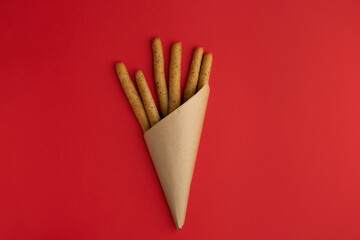 Grissini sticks wrapped in paper on a bright red background