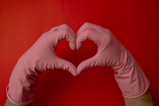 Heart shaped with hends in pink latex gloves. Red background. Valentine's day in time of Coronavirus. Love concept.