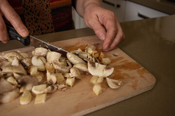 top view, woman's hand is cutting the mushrooms on the cutting board, slicing the mushrooms in kitchen.selective focus.