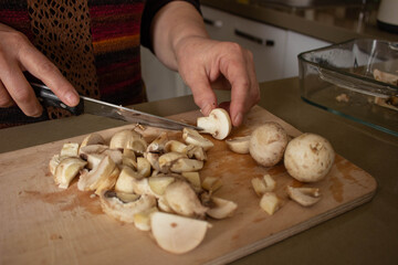 old woman hand cutting mushrooms, preparing mushroom slices for healthy food. selective focus.
