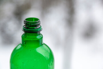 Part of bright green plastic bottle on blurred light background