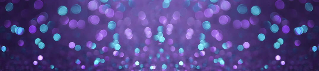 Abstract colorful green and purple bokeh on dark background.