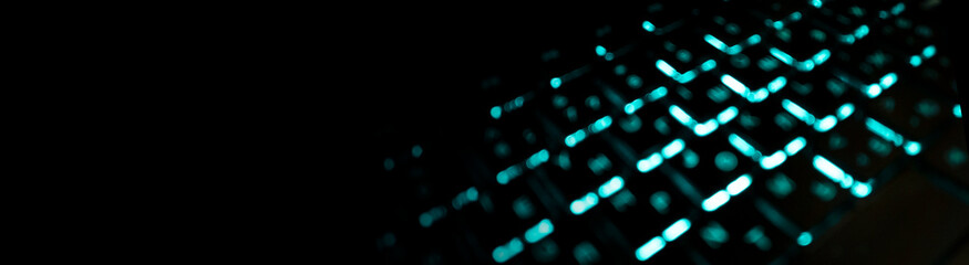 Black abstract background with defocused keyboard with turquoise backlight