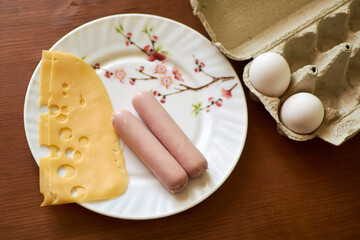 poor food - two sausages and a slice of cheese on a plate.