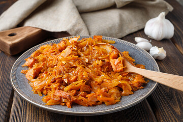 Stewed or braised cabbage in a plate on a wooden table.