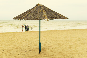 Beach umbrella made of straw by the sea.
