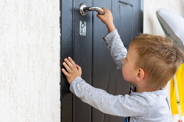 Young boy in front of a closed door.