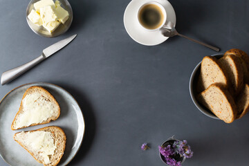 Homemade carrot bread with bran, butter and a cup of coffee on a gray background. Copy space. Top view. Copy space.