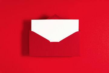 Red envelope with empty white paper on red background. Flat lay, top view, copy space
