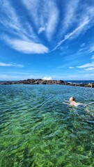 Child swimming in rock pool on vibrant summer day in Kiama, NSW Australia