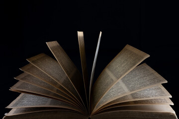 front view of an ancient old yellowed book open on a black background. space for text on the top