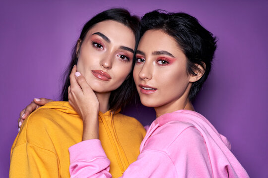 Two Asian And Caucasian Girls Lesbian Couple Hugging Looking At Camera, Close Up Portrait. Cool Generation Z Women Dating In Love Isolated On Purple Background. Lgbtq, Stylish Makeup Concept.