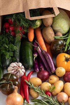 Flat Lay View Of Fruits And Vegetables Spilling Out Of A Paper Bag Onto White Counter Top