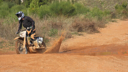 Zoom photo of motocross professional rider in action performing high speed stunts in dirt and mud...
