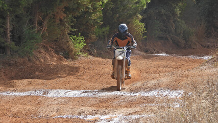 Zoom photo of motocross professional rider in action performing high speed stunts in dirt and mud...