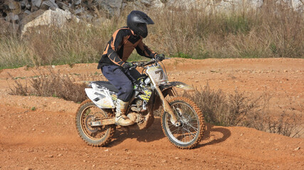 Zoom photo of motocross professional rider in action performing high speed stunts in dirt and mud terrain