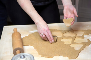 Female hands are preparing homemade cookies in the shape of heart. Horizontally. 