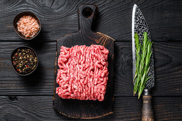 Raw mince lamb, ground meat with herbs and spices on a wooden cutting board. Black wooden...