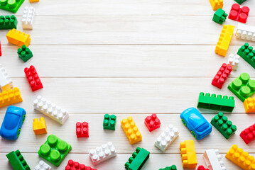 Top view of colorful plastic toy bricks on a white wooden background. Baby kids toys background