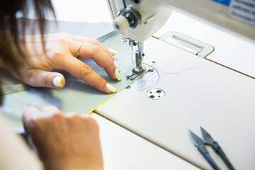 Woman hands with fabric at sewing machine