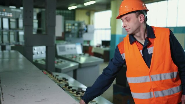 Engineer wearing an orange protective mask, hand finger press button controling cnc machine, workers operating factory machinery in warehouse machinery factory.