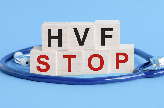 Wooden block with words HVF Stop - with stethoscope on the table, insurance and medical concept, blue background