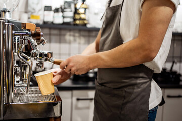 The barista professionally cooks a fragrant cappuccino for the client. A stylish Italian coffee machine in the cafe prepares coffee to take away. your own small business in the city