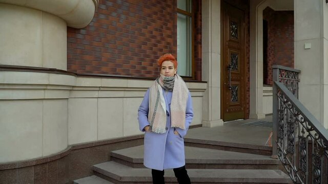 Girl in a blue coat and red hair posing at the camera