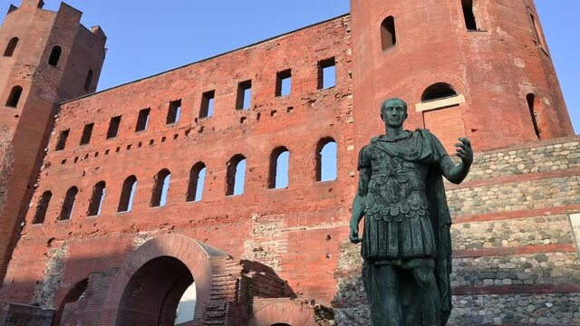 Turin, Italy. Beautiful view of the ancient Roman towers of the city, called Porta Palatina. In evidence an ancient Roman statue.