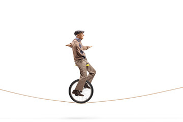 Elderly man riding a unicycle on a rope © Ljupco Smokovski