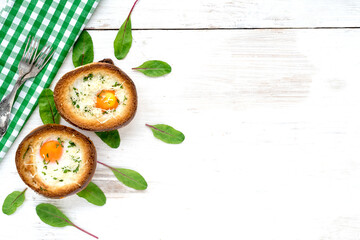 Baked eggs in round buns with cheese on a white wooden background. Breakfast top view