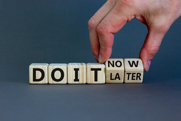 Do it now symbol. Businessman hand turns cubes and changes words 'do it later' to 'do it now'. Beautiful grey background. Business and do it now concept. Copy space.