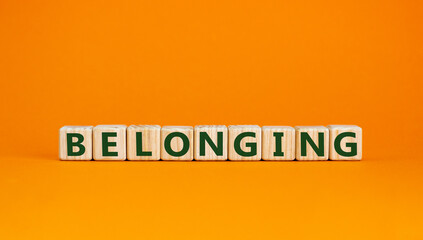 Belonging and better inclusion symbol. Belonging word on wooden cubes on beautiful orange background. Business, inclusion and belonging concept, copy space.