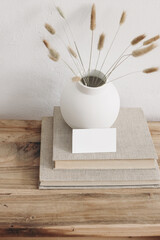 Business card mockup on vintage wooden table. Modern ceramic vase with dry Lagurus ovatus grass and...