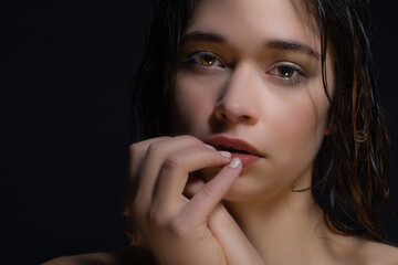 A sad young woman looks at the camera blankly. The woman is depressed due to loneliness and isolation. The Mental Effects of Isolating and Closing Your Home During Quarantine. Woman's face on black.