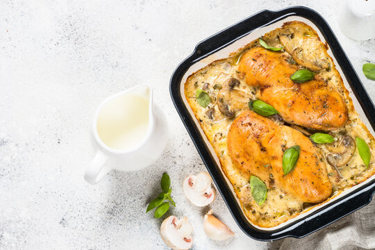 Baked chicken breast with mushrooms in cream sauce. Top view on white kitchen table.