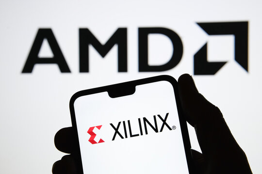Manchester / United Kingdom - October 21, 2020:  AMD to Acquire Xilinx, Concept. XILINX logo seen on the silhouette of smartphone in a hand and blurred AMD blurred logo on the background.