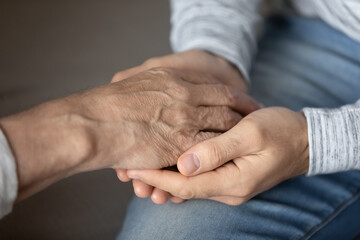 Crop close up of elderly father and adult son hold touch hands showing love and care in family...