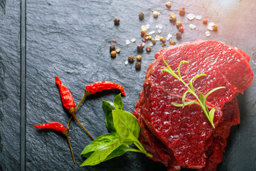 Raw steak meat from deer on the bridlic  chopping board  with ingredients as a sea salt, pepper,...