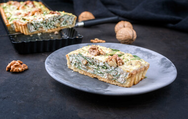 Modern style traditional French Autumn walnut spinach tarte slice served as close-up on a design plate