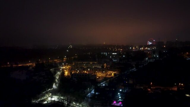 Kharkiv city center drone 4k view from  Botanical garden Sarzhyn Yar at night. Aerial view on city lights streets and Ferris wheel in background