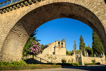 Fototapeta premium Vouzela Mother Church framed by the arch of the railway bridge in Vouzela, Portugal, on a sunny day.