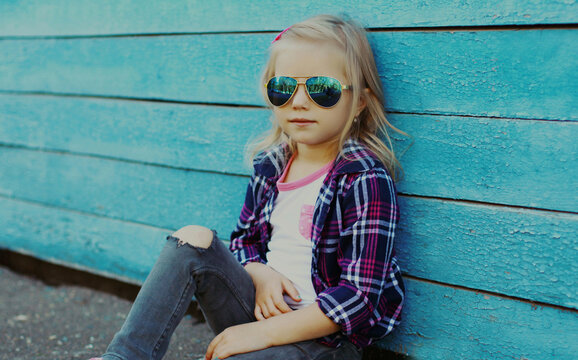 Portrait of stylish little girl child posing on a blue wooden background