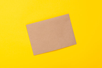 Sheet of craft paper brown color on yellow background. Clean envelope. Handmade hobby material. Wrapping. Handicraft goods store. Recyclable. Card with copy space and free text place. Natural. Eco